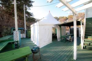 a deck with a white tent and a table and benches at Gangneung Maison de Rose in Gangneung