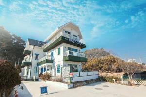 a large white building with a balcony on top of it at Gangneung Maison de Rose in Gangneung +4 photos