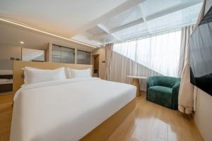 a bedroom with a large white bed and a green chair at MEI DI DU JIA HOTEL in Shanghai +35 photos