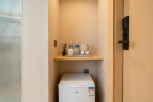 a small bathroom with a washer and dryer on a shelf at MEI DI DU JIA HOTEL in Shanghai