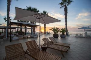 a patio with chairs and an umbrella and palm trees at Dioscuri Bay Palace in San Leone