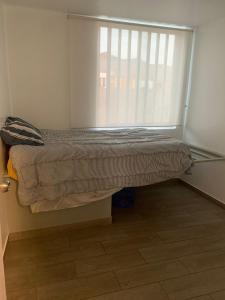a bed in a room with a window with blinds at Acogedores pisos en el valle de Mala in Mala