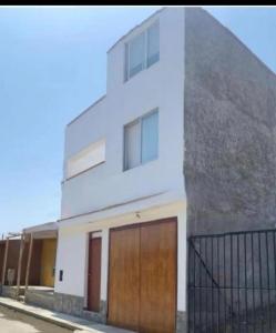 a white house with two doors and a fence at Acogedores pisos en el valle de Mala in Mala