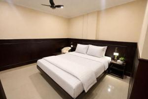 a bedroom with a large bed with white sheets at Landmark Inn in Lanka
