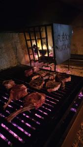 Eine Gruppe von Fleischstücken, die auf einem Grill im Kamin zubereitet werden in der Unterkunft Gran Malbec in Ciudad Lujan de Cuyo