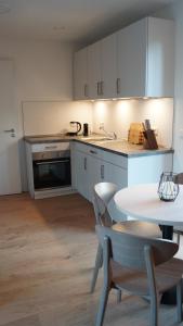 cocina con armarios blancos, mesa y fregadero en Haus Biederstaedt & LivJana, en Ottersberg