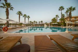 a large swimming pool with palm trees in a resort at Dioscuri Bay Palace in San Leone
