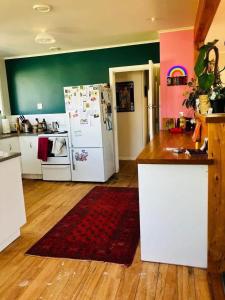 a kitchen with a white refrigerator and a red rug at Rainbow Lodge in Motueka