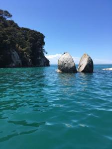 two large rocks in the water near the shore at Rainbow Lodge in Motueka