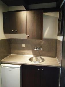 a kitchen with a sink and brown cabinets at Sunny views studios in Agios Gordios