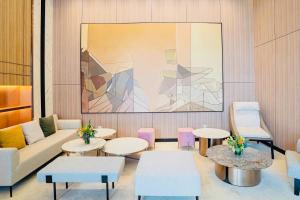 eine Lobby mit Tischen und Stühlen und einem Gemälde in der Unterkunft Hermes Housing- Masteri West Heights in Hanoi