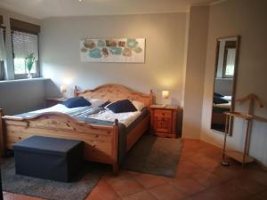 a bedroom with a large wooden bed and a mirror at Landhaus am Brubbel in Wallenborn