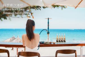 Eine Frau sitzt an einer Bar am Strand in der Unterkunft MGM Grand Sanya in Sanya + 88 Fotos