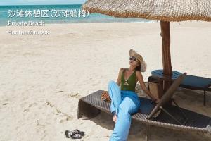 Eine Frau auf einem Stuhl am Strand in der Unterkunft MGM Grand Sanya in Sanya