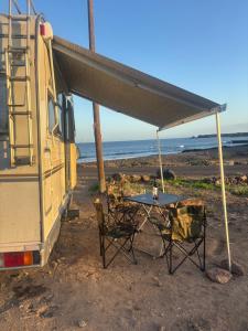 einen Tisch und Stühle unter einem Zelt neben einem Wohnwagen in der Unterkunft Palmi Caravan in Poris de Abona + 3 Fotos