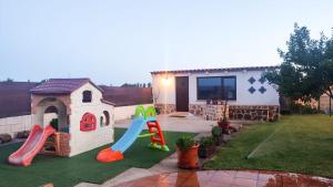 einen Hinterhof mit einem Spielplatz mit Rutsche und einem Haus in der Unterkunft La Casona del Bullaque in El Robledo