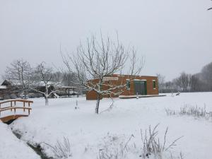 un bâtiment dans une cour enneigée avec un banc dans l'établissement Weihersmühle, à Fladungen