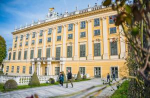 people walking in front of a large yellow building at Ibercity Wien Schönbrunn in Vienna