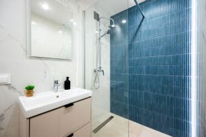 a bathroom with a sink and a shower with blue tiles at Apartament Baltic Panorama ProstyWynajem Parking in Zaspa +13 photos