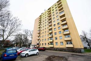 a large building with cars parked in front of it at Apartament Baltic Panorama ProstyWynajem Parking in Zaspa