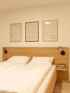 een slaapkamer met een wit bed met drie schilderijen aan de muur bij Geidorf Residenz - Serviced Apartments & Parking in Graz