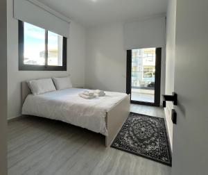 a white bedroom with a bed and two windows at AFRODITI Living in Nicosia