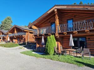 a log cabin with chairs and umbrellas in front of it at Chalet Marmotte am Nassfeld in Hermagor