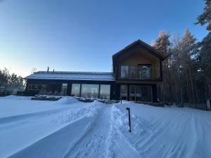 a house in the snow with a snow covered driveway at Hulppea merenranta hirsitalo in Oulu