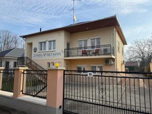 een huis met een hek ervoor bij Zama Apartman in Hajdúszoboszló