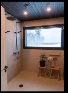 a bathroom with a window and a plant and stool at Hulppea merenranta hirsitalo in Oulu