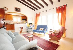 een woonkamer met een bank en stoelen en een keuken bij Calypso in Jávea +15 foto's