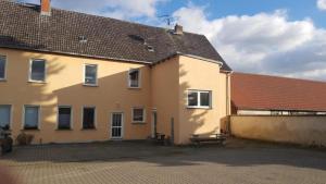 ein gelbes Gebäude mit einer Bank davor in der Unterkunft Pension Karsten Mertens in Gardelegen