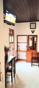 a living room with a table and a tv on the wall at Bee Line Cinnamon Estate Villa in Dickwella