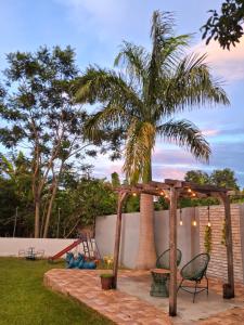 eine Terrasse mit einer Palme und einer hölzernen Pergola in der Unterkunft Casa de campo 18 km do Autódromo Velocitta in Mogi-Guaçu
