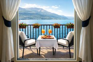 a balcony with a table and chairs and a view of the water at Hotel Meridiana in Bellano