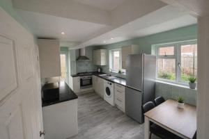 une grande cuisine avec un réfrigérateur et une table dans l'établissement Canterbury Luxe Stay, à Hackington