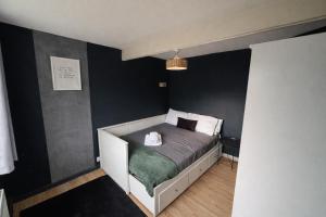 une chambre avec un lit dans une pièce aux murs noirs dans l'établissement Canterbury Luxe Stay, à Hackington