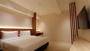 a bedroom with a bed and a flat screen tv at WYNS Hotel Bandung in Bandung