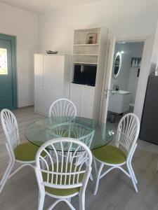 una sala da pranzo con tavolo in vetro e 4 sedie di villa Elaionas a Tsivarás