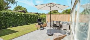 a patio with an umbrella and chairs and a television at The Pelican in Warmenhuizen