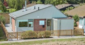 a small house with a fence in front of it at The Pelican in Warmenhuizen
