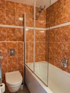 een badkamer met een bad, een toilet en een douche bij The Pelican in Schoorldam +14 foto's