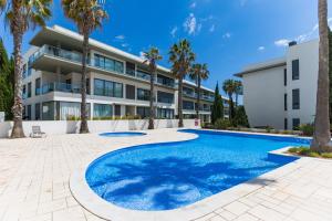 an apartment building with a swimming pool and palm trees at Cavalo Preto Ocean Breeze Apartment in Forte Novo Quarteira in Quarteira