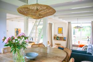 a dining room with a table with a vase of flowers at Strandbries in Warmenhuizen