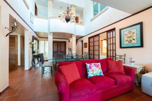 Una sala de estar con un sofá rojo y un comedor. en Villa De Palma Oceanfront Community w Generator, en Brenas