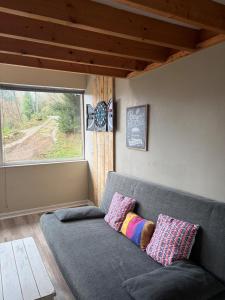 ein graues Sofa in einem Zimmer mit Fenster in der Unterkunft Maison à 5mn de Honfleur in Fourneville