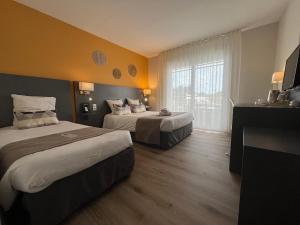 ein Hotelzimmer mit zwei Betten und einem Fenster in der Unterkunft L'Espadon in Saint-Jean-de-Monts + 49 Fotos