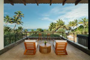 een balkon met tafels en stoelen en palmbomen bij Nyne Hotels LUXE Anugrah - Bentota in Bentota
