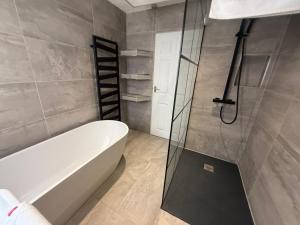 een badkamer met een bad en een glazen douchedeur bij Dalton House - Private Parking in Blackpool