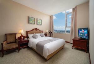 a hotel room with a large bed and a television at Kunming Plateau Pearl Hotel in Kunming